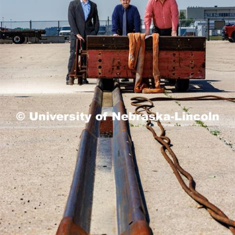 From left: Cody Stolle, Josh Steelman and Ron Faller lean against a sled connected to a ground anchor. The sled will be pulled to at a high speed to test the strength of the anchor for stopping it. Cody Stolle, Research Assistant Professor and Assistant Director of the Midwest Roadside Safety Facility is leading a group researching better checkpoint barriers to help the Department of Defense. June 5, 2023. Photo by Craig Chandler / University Communication.