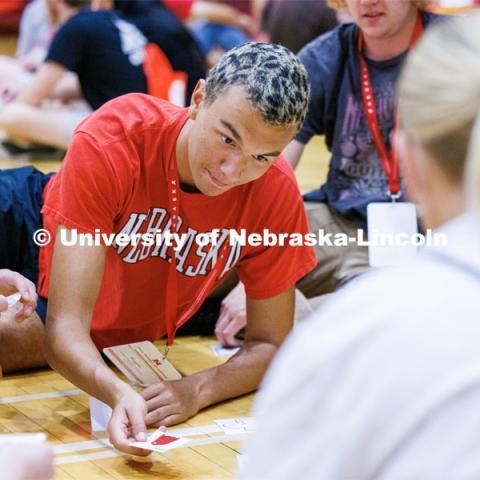 Braytn Nespor of Omaha stretches to place his card onto a pile. NSE students were sorting cards into piles organized by things to do this summer and when they arrive on campus. New Student Enrollment. June 7, 2023. Photo by Craig Chandler / University Communication.