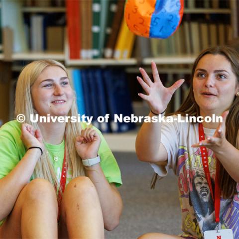 Kennedy Malo of Lakeville, Minnesota, grabs a numbered beachball as Bradie Johnson of South Sioux City, Nebraska, pulls her arms back. After catching the ball, each NSE person answers a question about themselves depending on which number their right index finger touches. New Student Enrollment ( NSE ) on City Campus. June 13, 2023. Photo by Craig Chandler / University Communication.