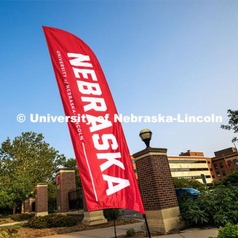 A Nebraska flag welcomes new students near the entrance gates on City Campus. New Student Enrollment. June 16, 2023. Photo by Craig Chandler / University Communication.