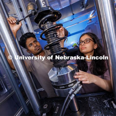 Gnyarienn Selva Kumar, left, and Doreen Rahman work on setting up a strut for a compression test. Both are masters students in mechanical engineering. They work in Cody Stolle’s lab in Whittier. July 27, 2023.  Photo by Craig Chandler / University Communication.