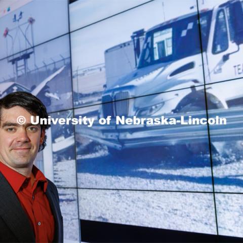 Cody Stolle, Research Assistant Professor, Midwest Roadside Safety Facility, stands in front of a crash video footage from testing done at the UNL Midwest Roadside Safety Facility. Cody Stolle lab in Whittier. July 27, 2023.  Photo by Craig Chandler / University Communication.