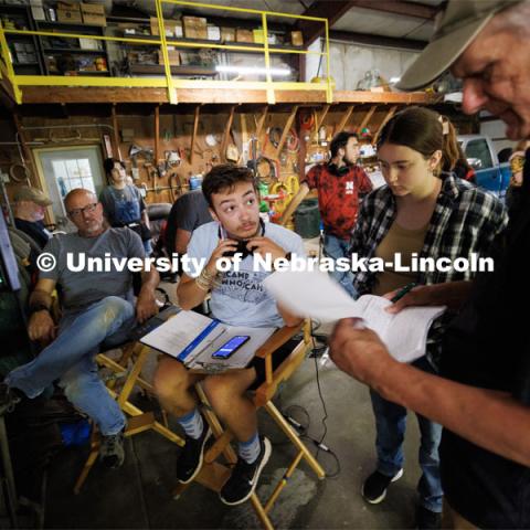 UNL student and script supervisor Charlie Major listens to comments by producer Jamie Vesay. At left is Richard Endacott and in the middle right is Grace Birkland, UNL student and second assistant cameraperson. Filming of the movie using UNL students as the production crew. Richard Endacott earned multiple awards for his screenplay, "Turn Over." Story about keeping the family farm operating in the modern era as two brothers come together via restoring an old tractor to help fund their operations. August 9, 2023. Photo by Craig Chandler / University Communication.