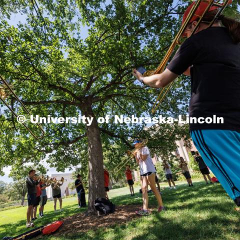 Janelle Johnson of Lincoln leads the trombone section while practicing in the shade of a tree in front of Pound Hall. Cornhusker Marching Band camp practice. August 14, 2023. Photo by Craig Chandler/ University Communication.
