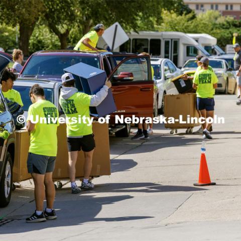 The Student Move-In Team swarms the line of cars outside Abel Residence Hall to unpack their belongings. First day of residence hall move-in. August 14, 2023. Photo by Craig Chandler/ University Communication.