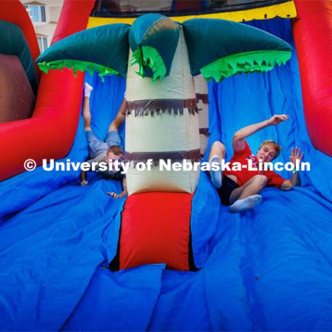 Cooper Garrett of Grand Island, right, rolls down the inflatable maze ahead of his competition. Block party at Harper Schramm Smith. August 17, 2023. Photo by Craig Chandler / University Communication.