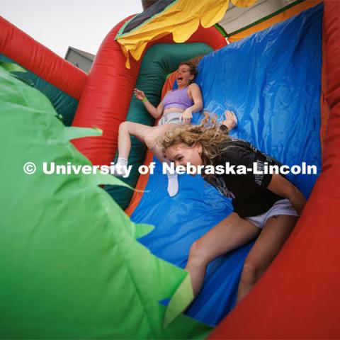 In a battle of new friends named Isabel(l), Isabell Zeller, slides down the inflatable maze ahead of Isabel Simpson at the Harper Schramm Smith block party. August 17, 2023. Photo by Craig Chandler / University Communication.