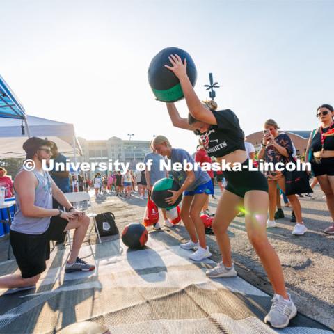 Students slam exercise balls into the ground at the Big Red Welcome Street Fest on the Memorial Stadium loop. Hundreds of clubs and organizations give away stuff to students. August 20, 2023. Photo by Craig Chandler / University Communication.