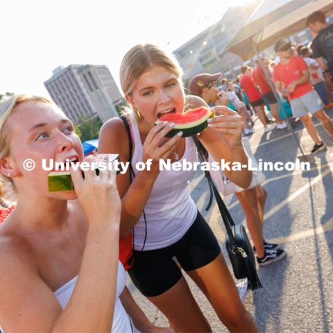 Two students enjoy a slice of watermelon at the Big Red Welcome Street Fest on the Memorial Stadium loop. Hundreds of clubs and organizations give away stuff to students. August 20, 2023. Photo by Craig Chandler / University Communication.