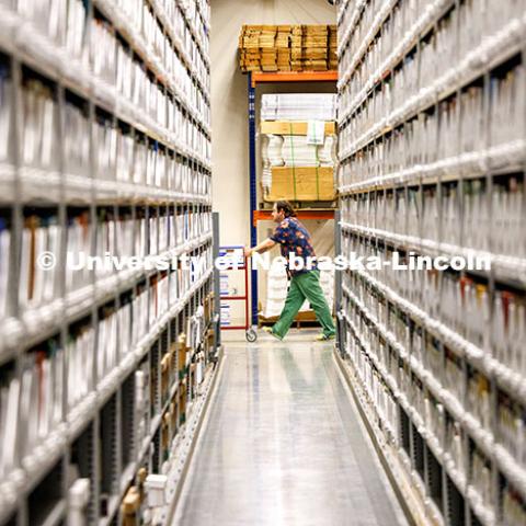 Josh Caster, Archives Manager for University Libraries, wheels a cart of materials to be refiled in the Library Depository Retrieval Facility on East Campus. September 29, 2023. Photo by Craig Chandler / University Communication and Marketing
