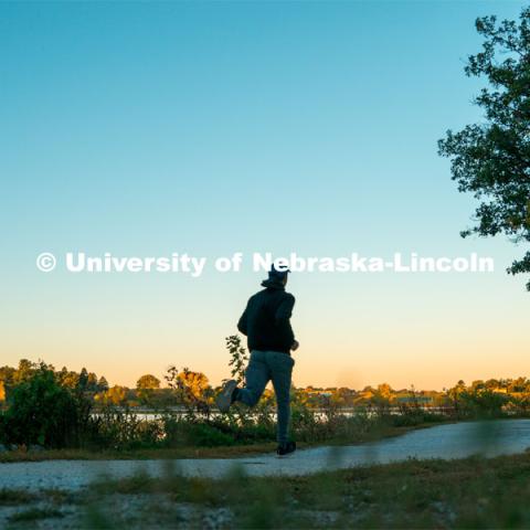 A jogger runs the walking path at Holmes Lake. About Lincoln at Holmes Lake. October 20, 2023. Photo by Matthew Strasburger / University Communication.