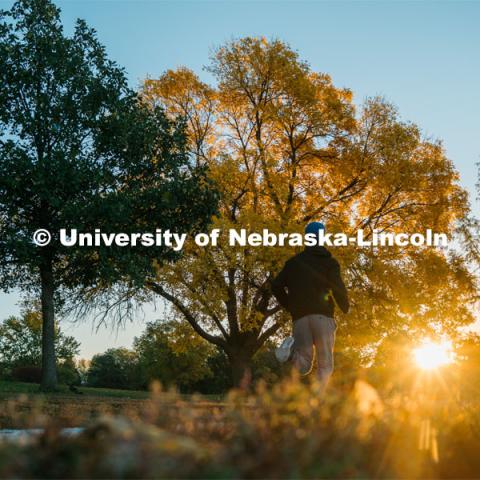 A jogger runs the walking path at Holmes Lake. About Lincoln at Holmes Lake. October 20, 2023. Photo by Matthew Strasburger / University Communication.