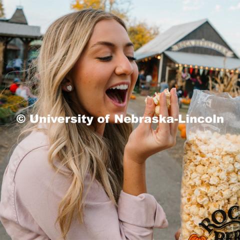 Husker Cheerleader Peyton Prussa enjoys a bag of popcorn at Roca Berry Farm. About Lincoln at Roca Berry Farm. October 22, 2023. Photo by Matthew Strasburger / University Communication.