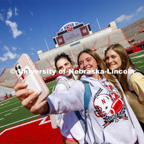 Sydney White, left, Morgan Wiseman and Gretchen Hodge, all juniors and Delta Delta Delta sorority members, take a selfie on the N in Memorial Stadium during the birthday party. Memorial Stadium 100th birthday party at the stadium. The free public event featured cake and visitors could walk onto the field. October 23, 2023. Photo by Craig Chandler / University Communication.