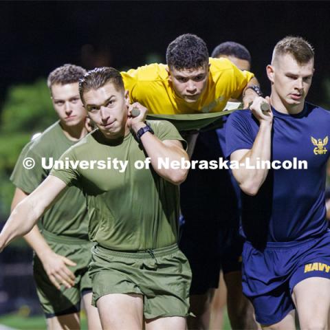 Navy midshipman Matthew Alarcon rides the litter during the casualty evacuation race. Each branch ran a timed 220 yard race for the male and female cadets and midshipman. ROTC Joint Field Meet is like an ROTC Olympics for the Nebraska cadets and midshipman. Army, Air Force and Navy/Marine cadets and midshipmen compete in events such as Maneuvering Under Fire, Log Sit-ups, Tug-Of-War, Casualty Evacuation and Ultimate Frisbee. Army beat Navy in a sudden death 4x400 relay to claim the title. October 26, 2023. Photo by Craig Chandler / University Communication.