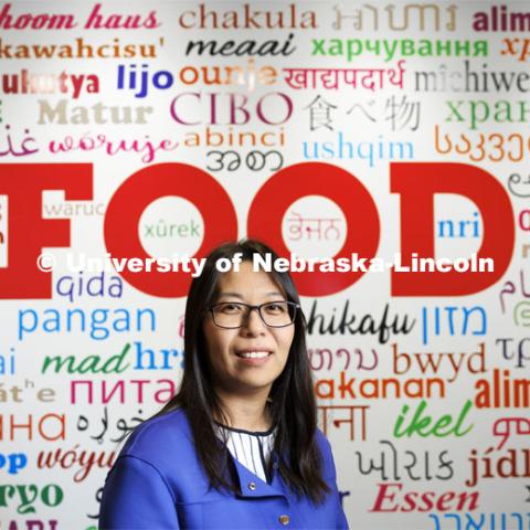 Bing Wang, Associate Professor of Food Science and Technology, is spearheading cutting-edge science to contain food safety risks in the U.S. and worldwide. Bing serves as an expert consultant at the national and international levels, and her UNL lab is in the forefront of using cutting-edge analytical methods in this area of science. She is in front of a wall in the Food Innovation Center that has the word “food” in multiple languages. November 3, 2023. Photo by Craig Chandler / University Communication and Marketing.