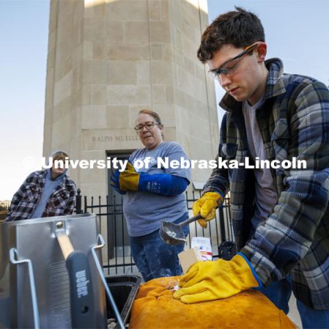 George Viehl, freshman, makes his pour into the mold of a pilgrims’ badge of Thomas Becket, former Lord High Chancellor of Great Britain, as Carolyn Twomey watches. Carolyn Twomey’s HIST211 History of the Middle Ages course metalcasts medieval pilgrims' badges over a fire at the base of the Mueller Tower Thursday morning. November 2, 2022. Photo by Craig Chandler / University Communication and Marketing.