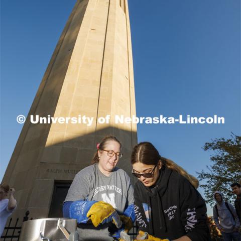 Carolyn Twomey talks with Lilli Reynolds as she opens her mold to reveal her pilgrim’s badge. Carolyn Twomey’s HIST211 History of the Middle Ages course metalcasts medieval pilgrims' badges over a fire at the base of the Mueller Tower Thursday morning. November 2, 2022. Photo by Craig Chandler / University Communication and Marketing