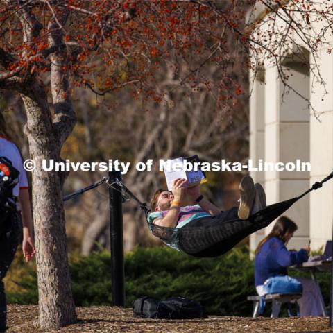 Alex Martinez, a senior from Lincoln, takes advantage of the 70-degree weather to lay in the hammock and do some reading. He said it was his first time in four years at UNL he has used the hammocks. Fall on city campus. November 15, 2023. Photo by Craig Chandler / University Communication and Marketing