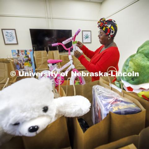 Domonique Cudjo, Assistant Director, Gender and Sexuality Center, attaches a gift tag to a bicycle being given to a little Husker. Holidays for Little Huskers. November 16, 2023. Photo by Craig Chandler / University Communication and Marketing.