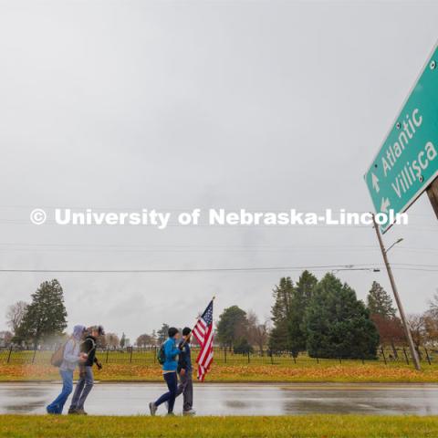 Iowa veterans walking the second day of the Ruck March walk along Hwy 83 east of Atlantic, Iowa, carrying the Nebraska v. Iowa game ball. The Things They Carry" ruck march involving military and veteran students from Iowa and Nebraska. To raise awareness about veteran suicide, through the week, the students walk in 20-mile shifts carrying 20-pound backpacks to commemorate the estimated 20 veterans who die by suicide each day. November 20, 2023. Photo by Craig Chandler / University Communication and Marketing.