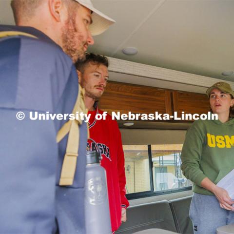 Jenalee Wimer, a senior Animal Science Pre-Veterinary Medicine student and Marine, helps Lincoln veterans (left) Pete Lass and McCain Vesa at the start of sign their wavers for the Monday afternoon session of the march. Ruck Marchers walk along Hwy 83 east of Atlantic, Iowa, carrying the Nebraska v. Iowa game ball. The Things They Carry" ruck march involving military and veteran students from Iowa and Nebraska. To raise awareness about veteran suicide, through the week, the students walk in 20-mile shifts carrying 20-pound backpacks to commemorate the estimated 20 veterans who die by suicide each day. November 20, 2023. Photo by Craig Chandler / University Communication and Marketing.