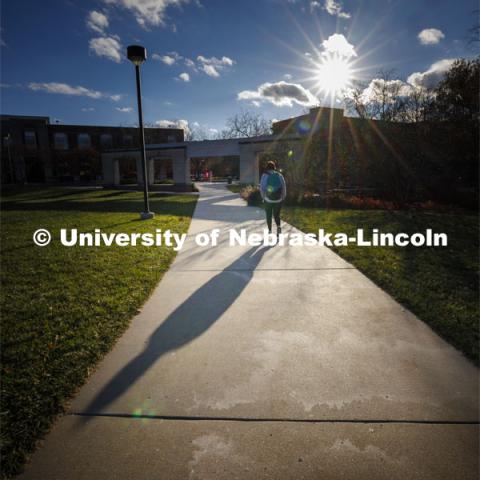 Long shadows are cast by a student walking on city campus. November 27, 2023. Photo by Craig Chandler / University Communication and Marketing.