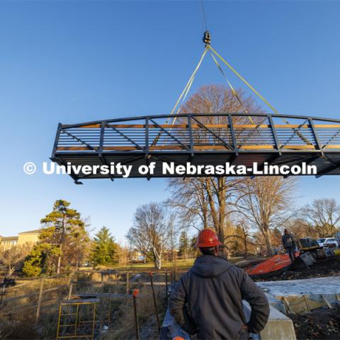 A 40-foot, three-and-a-half-ton bridge is lifted into place over Dead Mans Run on East Campus’ Maxwell Arboretum. December 5, 2023. Photo by Craig Chandler / University Communication and Marketing.