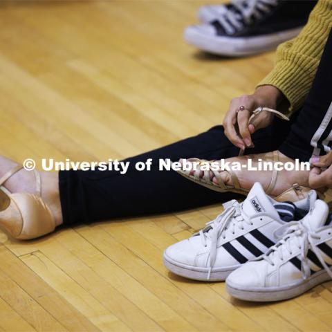Paige Myers puts her dancing shoes on before the rehearsal. Ballroom Dancing Club works through their final practice in the Nebraska Union Ballroom Thursday night before Saturday’s show. December 7, 2023. Photo by Craig Chandler / University Communication and Marketing.