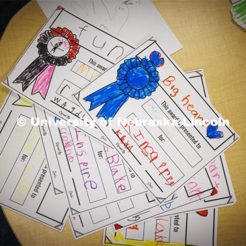 A pile of awards from the kindergarten class for Crandall Blake lay on a table. Blake student teaches her kindergarten class at Lakeview Elementary. She had her students sign a pair of white high-top shoes which she will wear at commencement so “her entire class can walk across stage with her. December 13, 2023. Photo by Craig Chandler / University Communication and Marketing