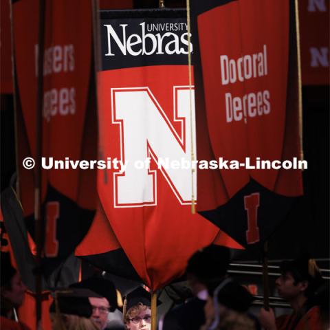 Student body president Paul Pechous holds the gonfalon during the Graduate Commencement at Pinnacle Bank Arena. December 15, 2023. Photo by Craig Chandler / University Communication and Marketing.