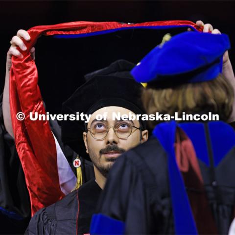 Mohammad Ali Takallou watches as his doctoral hood is lowered over his head. Graduate Commencement at Pinnacle Bank Arena. December 15, 2023. Photo by Craig Chandler / University Communication and Marketing.