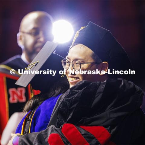 Biquan Zhao hugs one of his advising professors after receiving his doctoral degree in natural resource sciences. Graduate Commencement at Pinnacle Bank Arena. December 15, 2023. Photo by Craig Chandler / University Communication and Marketing.