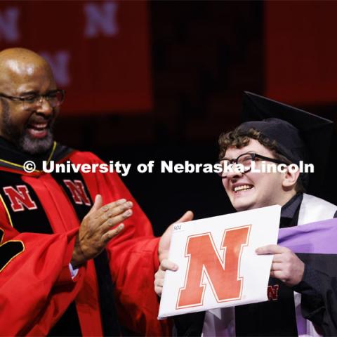 Sebastian Toalson gestures to family and friends after Chancellor Bennett had the last graduate to walk across stage stop and show the diploma to the crowd. Graduate Commencement at Pinnacle Bank Arena. December 15, 2023. Photo by Craig Chandler / University Communication and Marketing.