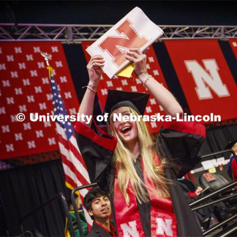 Elisa Stoike shows her CEHS diploma to family and friends. Winter undergraduate commencement in Pinnacle Bank Arena. December 16, 2023. Photo by Craig Chandler / University Communication and Marketing.