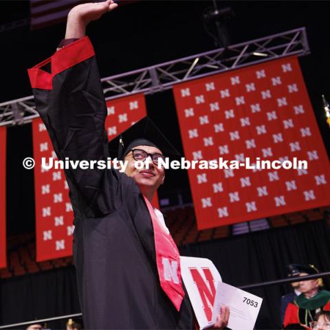 Zoyace Shrestha waves to family and friends after receiving his Engineering degree. Winter undergraduate commencement in Pinnacle Bank Arena. December 16, 2023. Photo by Craig Chandler / University Communication and Marketing.