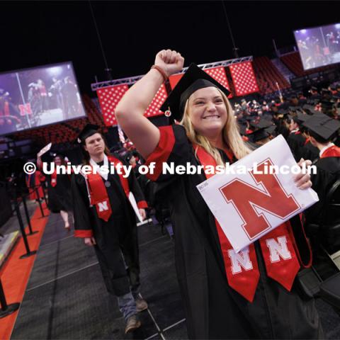 Megan Fehr fist pumps the air as she shows her communication studies diploma to family and friends. Winter undergraduate commencement in Pinnacle Bank Arena. December 16, 2023. Photo by Craig Chandler / University Communication and Marketing.