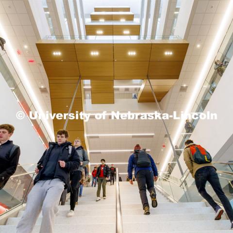 A long straight staircase separates the first and second floor before the stairs wind up the east side of the atrium. First day of classes in Kiewit Hall. January 22, 2024. Photo by Craig Chandler / University Communication and Marketing.