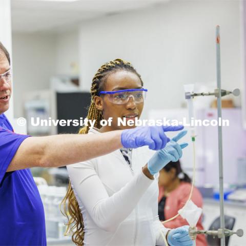 Favour Wanjoku and biochemistry instructor Mark Behrens discuss the test setup to drip egg white solution to awaiting test tubes. Students isolate and purify lysozyme from actual egg whites in BIOC 401L - Laboratory for Elements of Biochemistry. February 13, 2024. Photo by Craig Chandler / University Communication and Marketing.