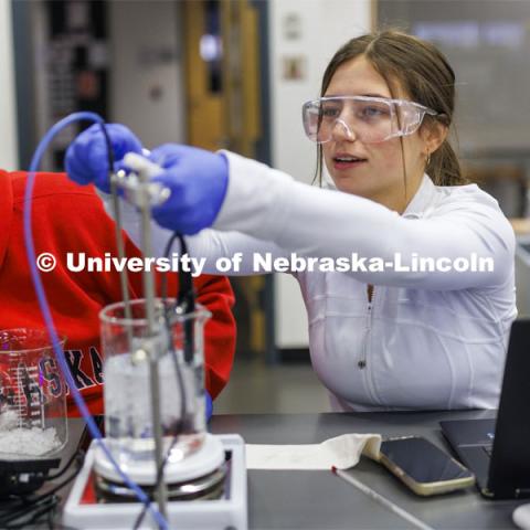 Grace Henry adjusts the heating and temperature probes in a sample fluid while lab partner Mayra Guerrero looks on. LIFE 120L - Fundamentals of Biology lab in Manter Hall. February 22, 2024. Photo by Craig Chandler / University Communication and Marketing.