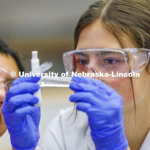 Grace Henry looks at a fluid sample while lab partner Mayra Guerrero looks on. LIFE 120L - Fundamentals of Biology lab in Manter Hall. February 22, 2024. Photo by Craig Chandler / University Communication and Marketing.