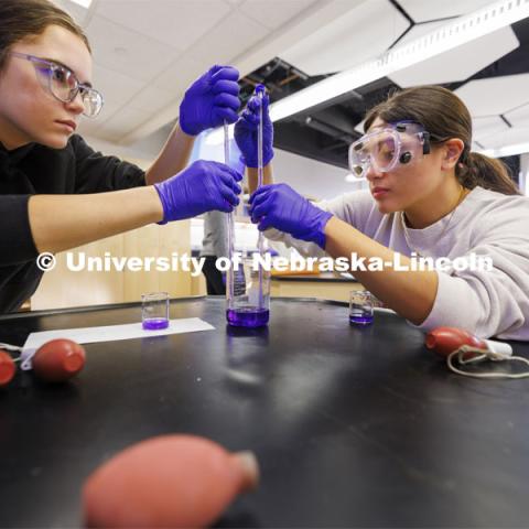 Emma Benson, left, and Johana Macias draw up crystal violet for a lab entitled “kinetics at work”. Hamilton Hall chemistry 110 lab. February 29, 2024. Photo by Craig Chandler / University Communication and Marketing.