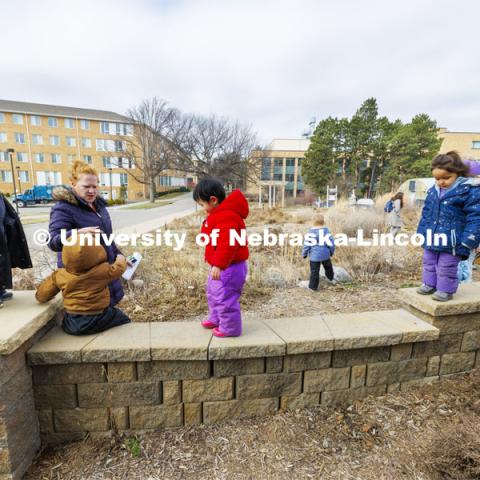 Madeline Williams helps the children as they walk along a low stone wall in the Backyard Farmer Garden. Students in the Ruth Staples Child Development Lab go on a field trip to the Nebraska East Union and a walk around campus. March 1, 2024. Photo by Craig Chandler / University Communication and Marketing