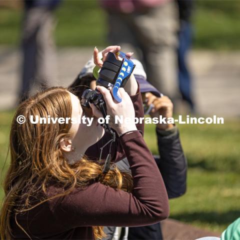 A student attempts to capture a photo of the eclipse using the glasses and her camera on East Campus. April 8, 2024. Photo by Kristen Labadie / University Communication.