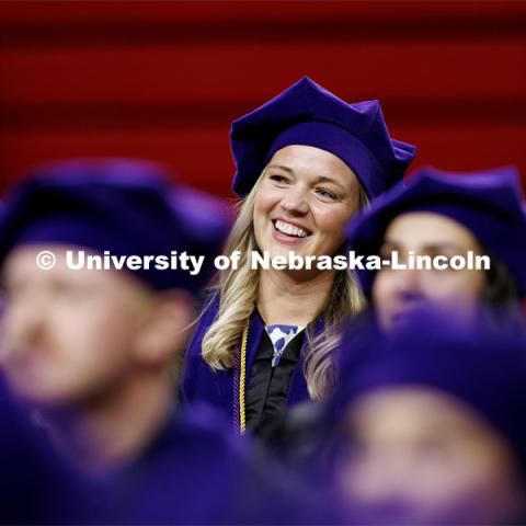 Tevyn Waddell smiles while listening to Murphy Cavanaugh’s remarks on behalf of the class of 2024.  College of Law commencement in Devaney on the volleyball court. May 3, 2024. Photo by Craig Chandler / University Communication and Marketing.