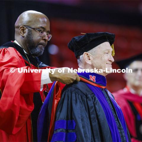 Larry Johnson is hooded by Chancellor Rodney D. Bennett after Johnson has awarded an honorary degree. College of Law commencement in Devaney on the volleyball court. May 3, 2024. Photo by Craig Chandler / University Communication and Marketing.