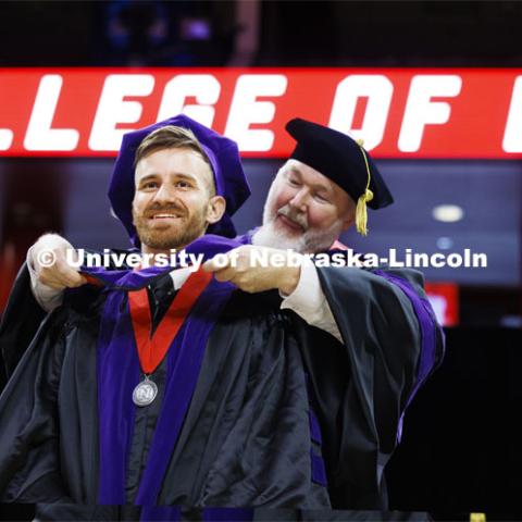 Peter Biedenweg receives his hood. College of Law commencement in Devaney on the volleyball court. May 3, 2024. Photo by Craig Chandler / University Communication and Marketing.