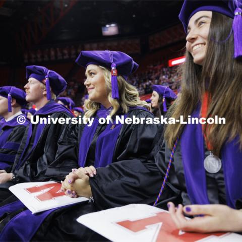 Emma Schlenkerand and Christina Schauer listen to final comments by Dean Richard Moberly after they had received their hoods. College of Law commencement in Devaney on the volleyball court. May 3, 2024. Photo by Craig Chandler / University Communication and Marketing.