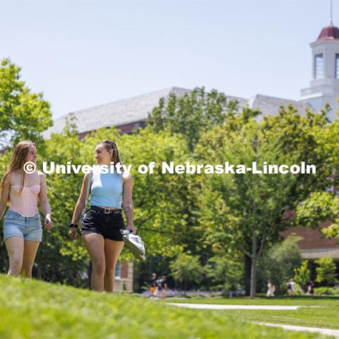Mason Nightingale and Madelein Woolard use the combination of warm weather and green grass to enjoy walking with their shoes off. Finals week on campus. May 14, 2024. Photo by Craig Chandler / University Communication and Marketing.