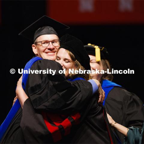 Johannah Rae Bashford-Largo hugs her dad, Professor Greg Bashford, after she received her psychology degree. At right is Maital Neta, her advising professor. Graduate Commencement. May 17, 2024. Photo by Craig Chandler / University Communication and Marketing.